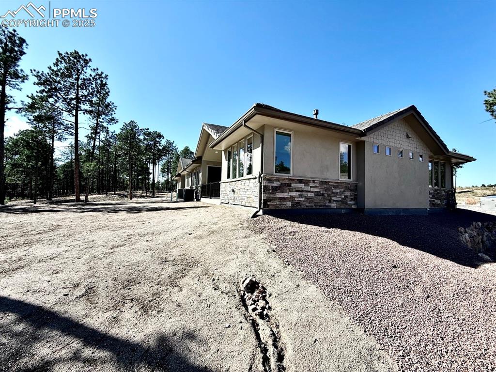 Image 28 of 32: View of side of home featuring stone siding and stucco siding