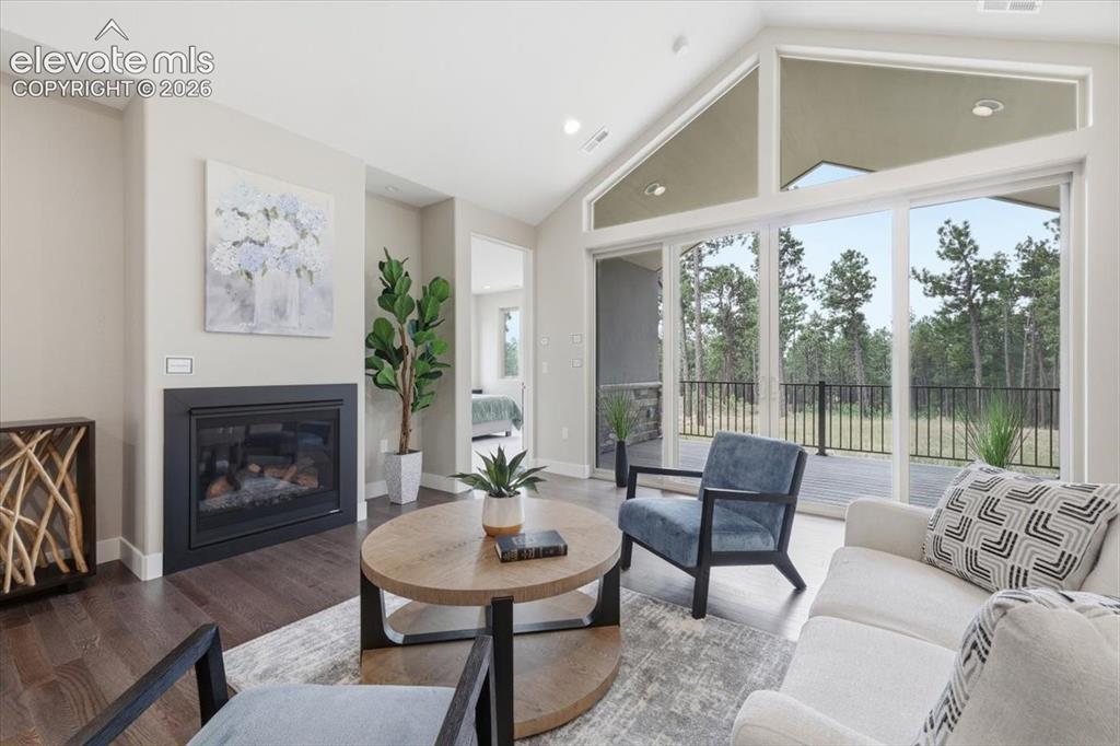 Image 6 of 18: Vaulted Living Room with Gas Fireplace, Wood Flooring, and Oversized Double