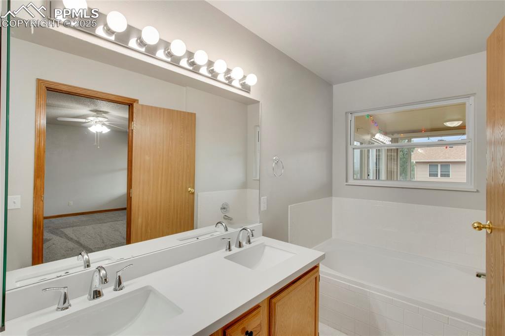 Image 14 of 27: Full bathroom with a garden tub, double vanity, and ceiling fan