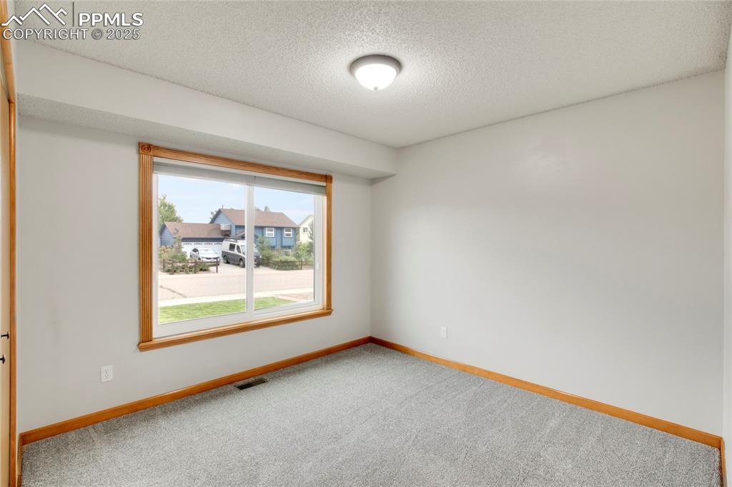 Image 15 of 27: Carpeted empty room with a textured ceiling and baseboards