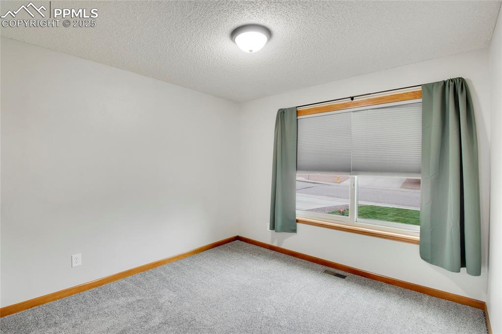 Image 17 of 27: Carpeted empty room with baseboards and a textured ceiling