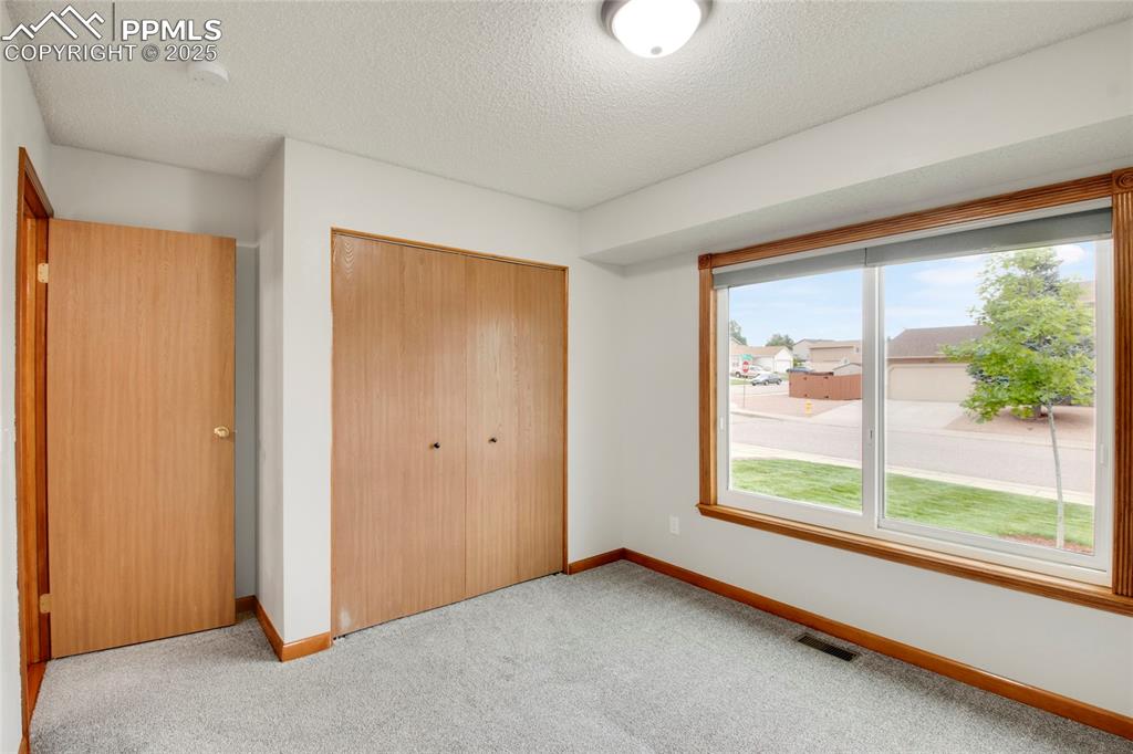 Image 18 of 27: Unfurnished bedroom with carpet, a closet, and a textured ceiling