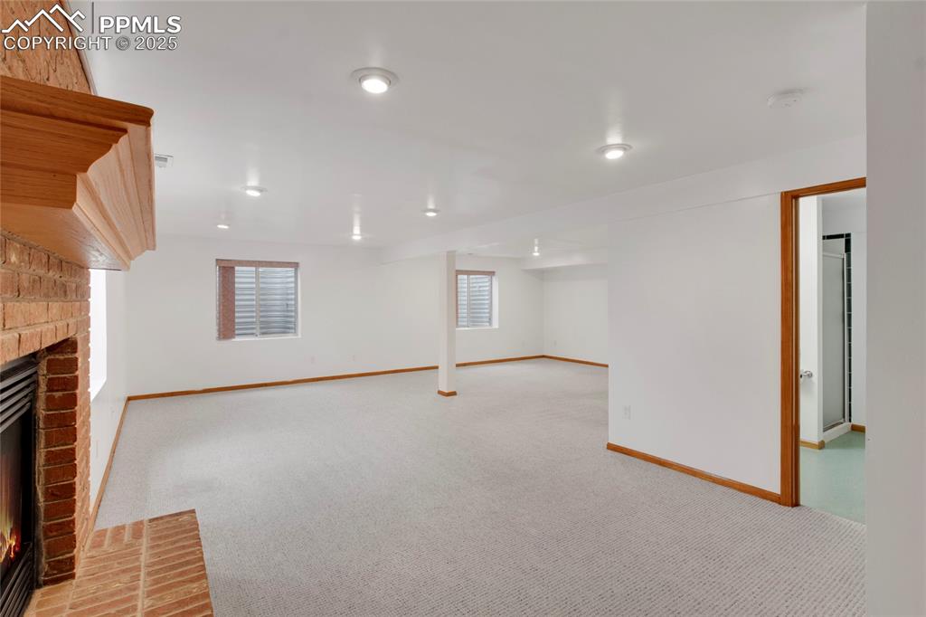 Image 20 of 27: Basement with a fireplace and carpet
