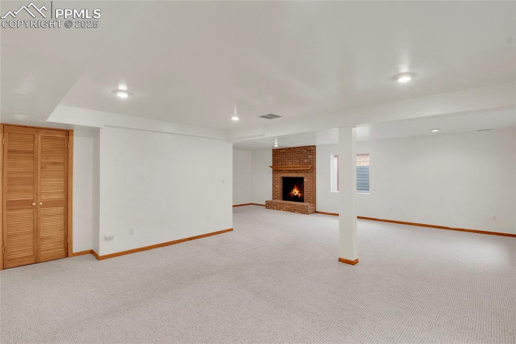 Image 23 of 27: Basement featuring a fireplace, light carpet, and recessed lighting