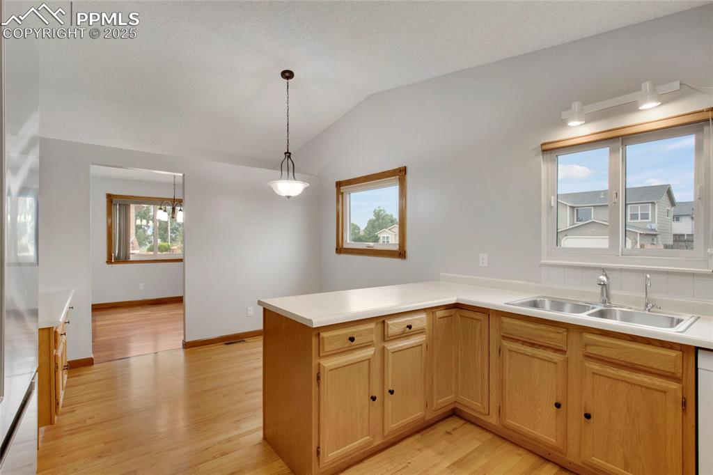 Image 8 of 27: Kitchen featuring light brown cabinetry, light countertops, light wood-styl