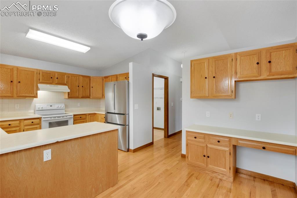 Image 9 of 27: Kitchen freestanding refrigerator, light countertops, light wood flooring, 