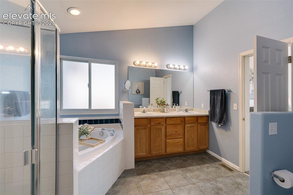 Image 23 of 50: Main level Primary Bathroom with tiled shower, soaking tub, and dual sink v