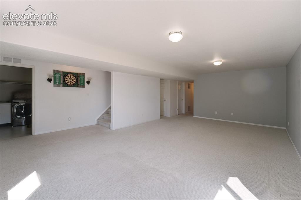Image 30 of 50: Large Basement Family Room with neutral carpet.