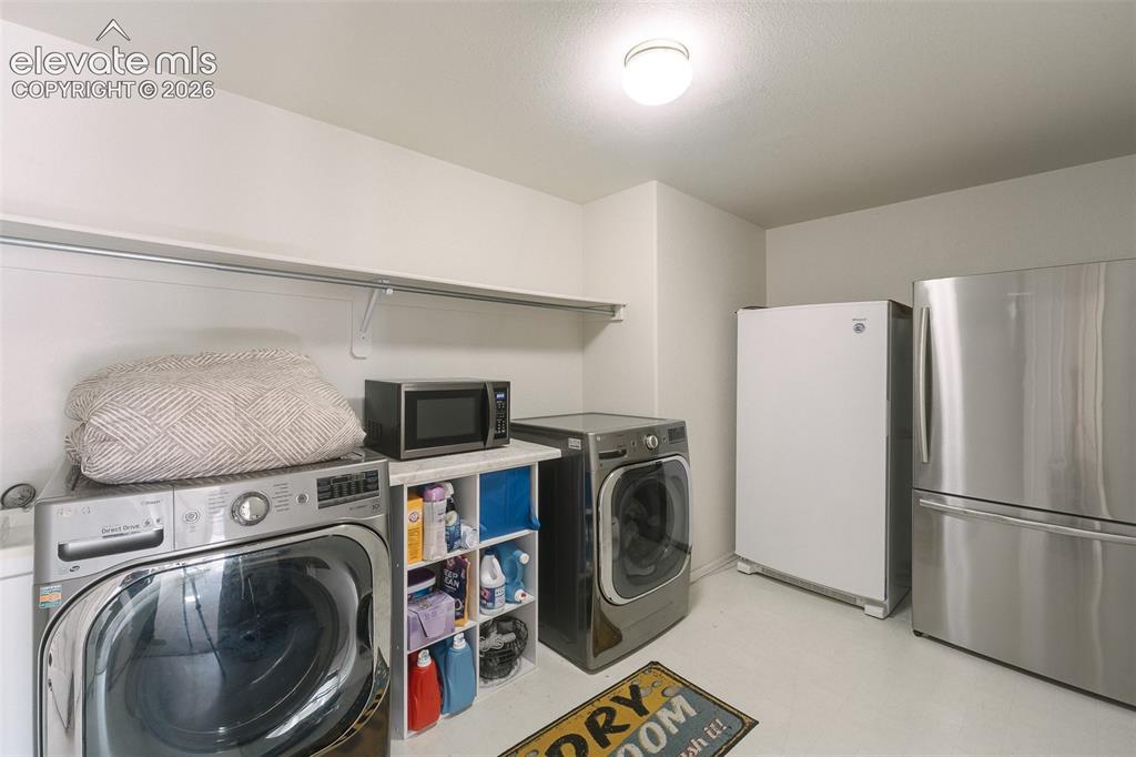 Image 31 of 50: Basement Laundry Room with built-in shelf, washer, dryer, stand up freezer,