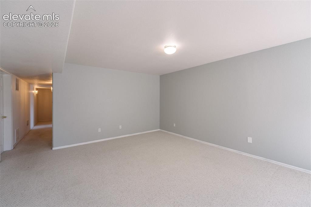 Image 33 of 50: Basement Family Room with hallway to the Bedrooms and Basement Bathroom.