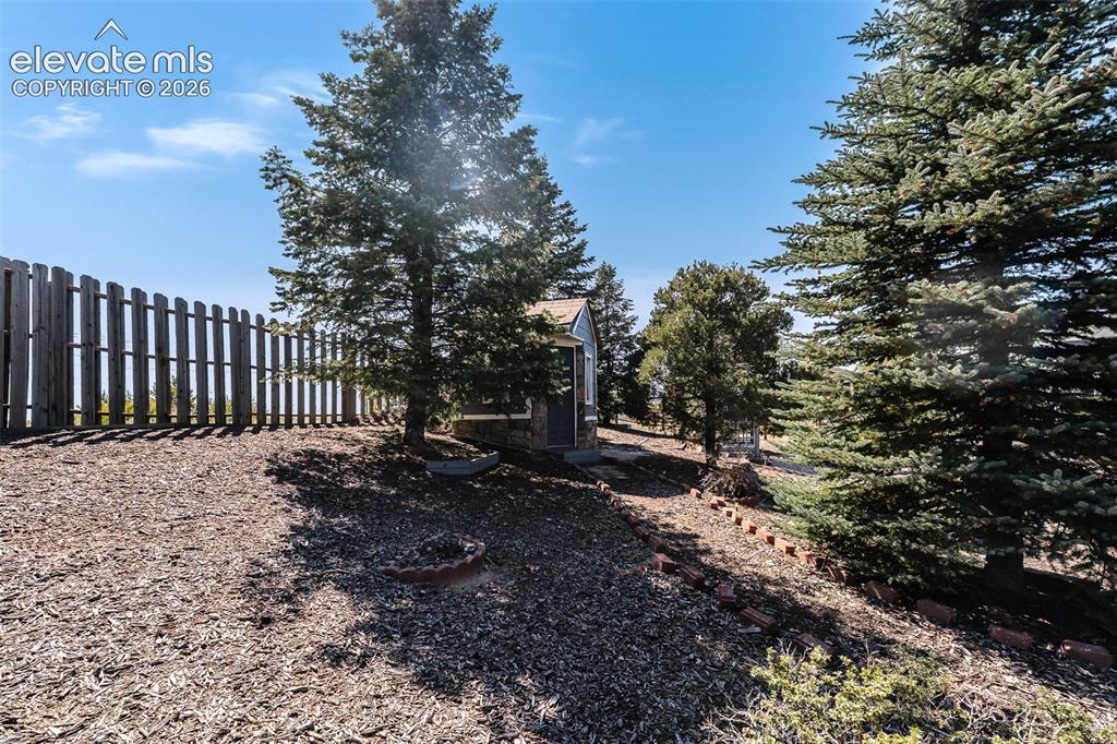Image 45 of 50: Fenced yard with mature trees for privacy.