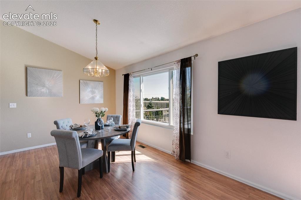 Image 6 of 50: The Dining Area has LVP flooring, an attractive light fixture, & looks out