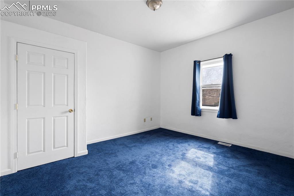 Image 12 of 21: Unfurnished room with baseboards and dark colored carpet