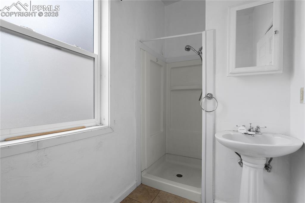 Image 16 of 21: Full bathroom with a shower stall and light tile patterned floors