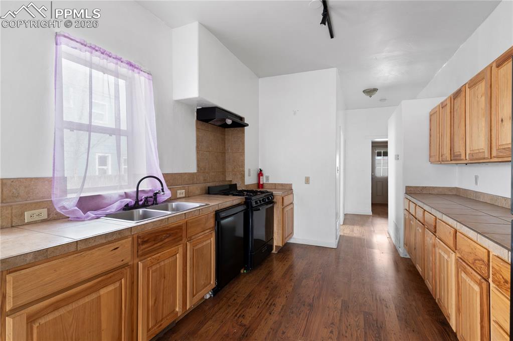 Image 5 of 21: Kitchen featuring tile counters, dark wood finished floors, black appliance