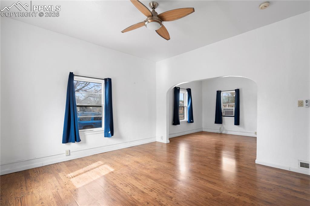 Image 6 of 21: Empty room featuring a ceiling fan, wood finished floors, arched walkways,