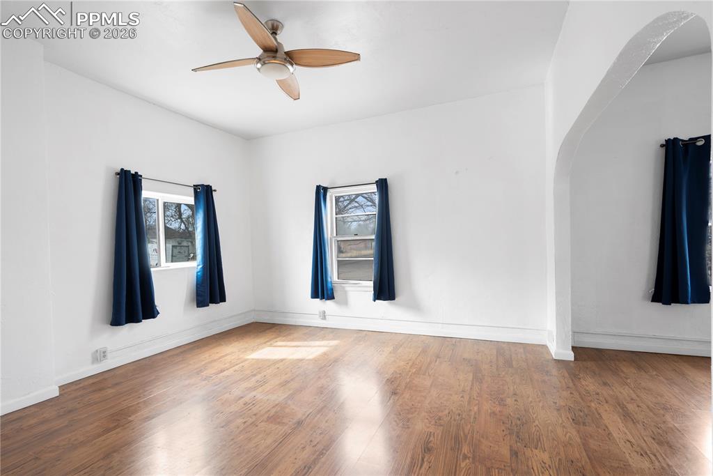 Image 8 of 21: Spare room featuring wood finished floors, ceiling fan, and arched walkways