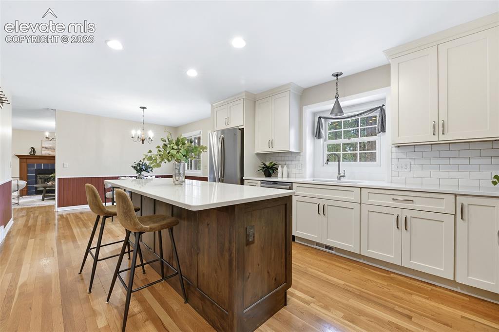 Image 16 of 50: Large island with counter seating, quartz counters and subway tile backspla