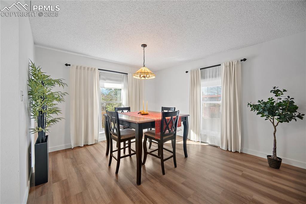 Image 8 of 49: Dining room features new flooring and large picture windows floor the space