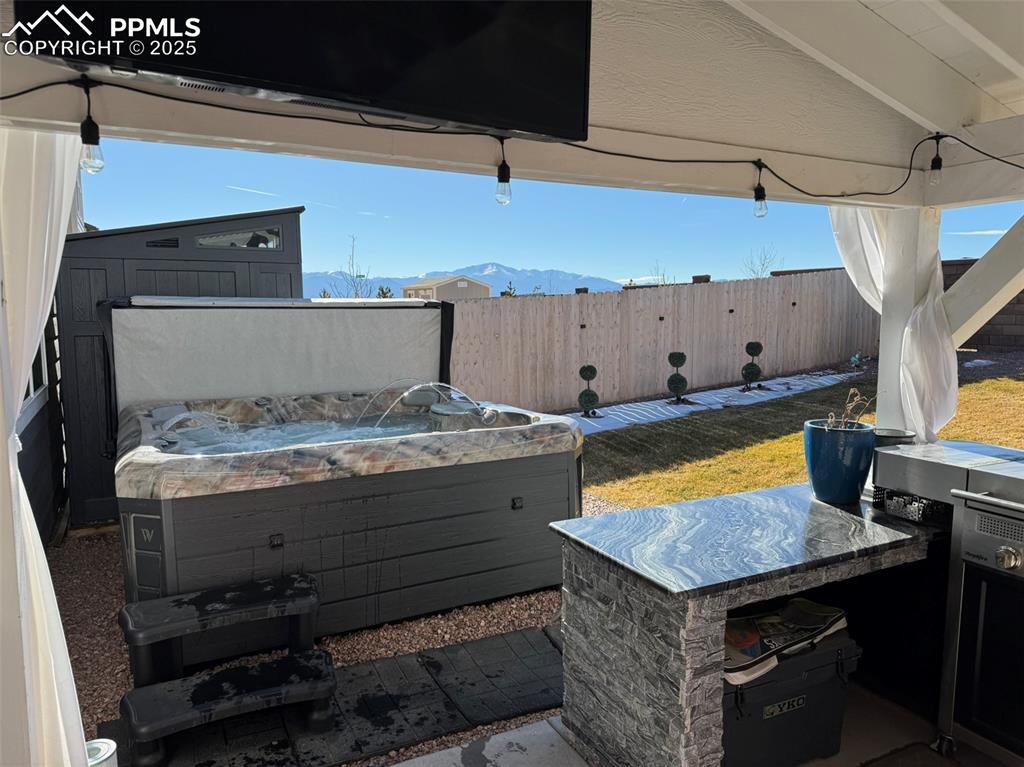 Image 6 of 37: Covered rear patio w hot tub and mountain view