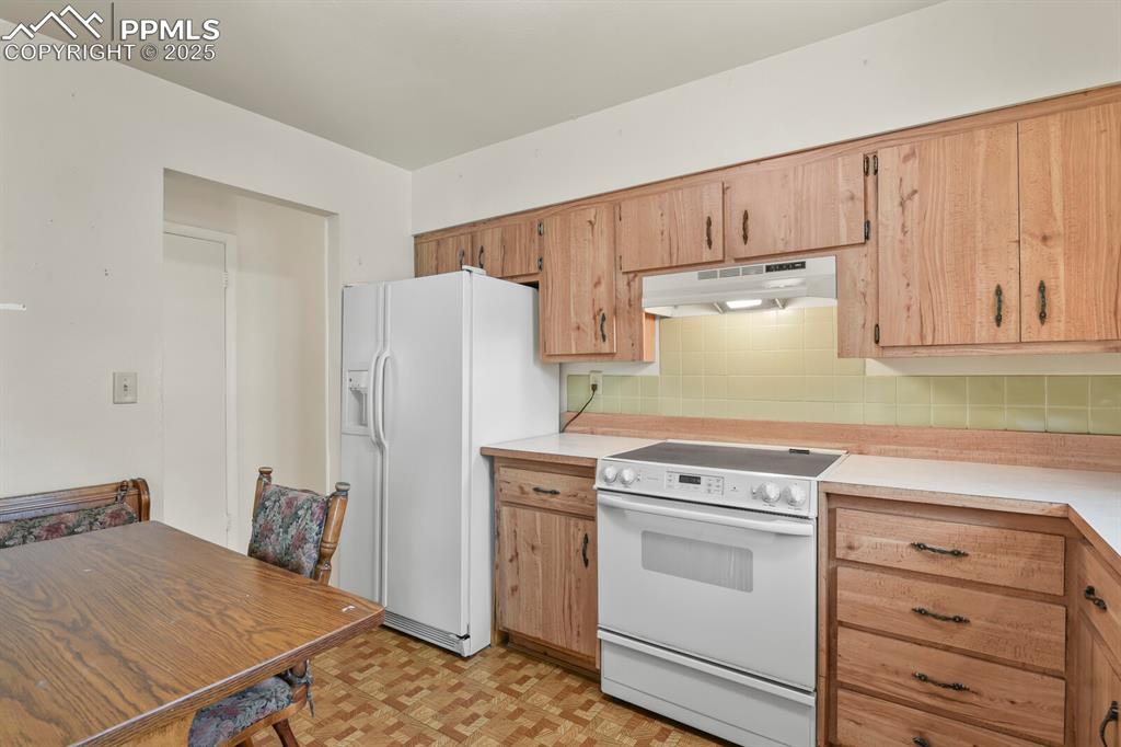 Image 10 of 26: Kitchen featuring white appliances, light countertops, backsplash, under ca