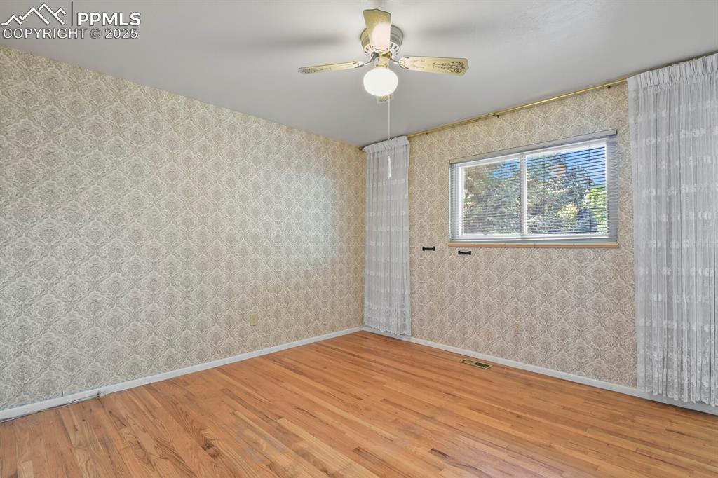 Image 12 of 26: Spare room featuring wood finished floors, wallpapered walls, and a ceiling