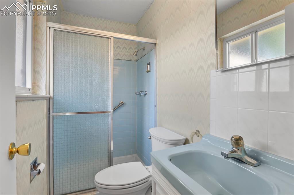 Image 14 of 26: Full bath with a shower stall, wallpapered walls, and vanity
