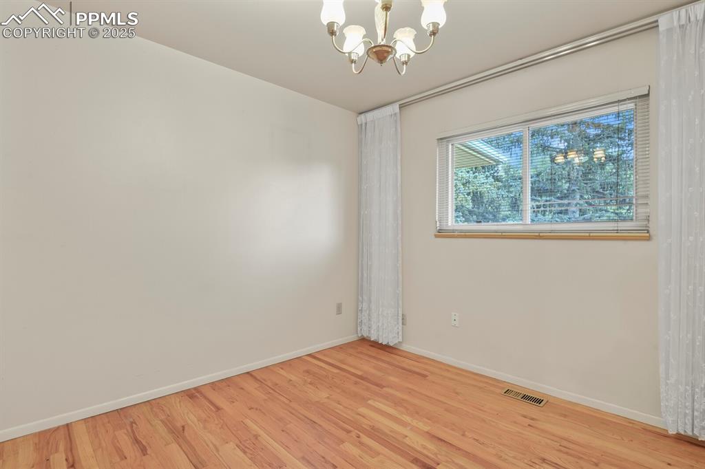 Image 15 of 26: Spare room featuring wood finished floors and a chandelier