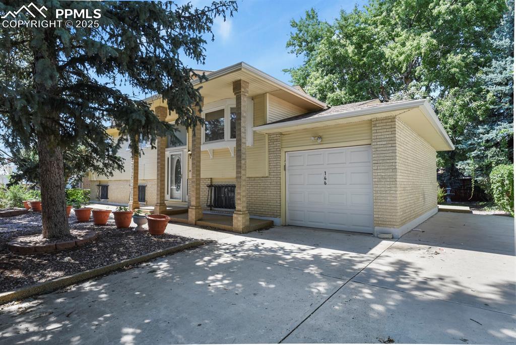 Image 2 of 26: View of front of house with brick siding, a garage, and concrete driveway