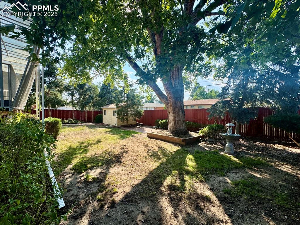 Image 23 of 26: Fenced backyard featuring a storage shed
