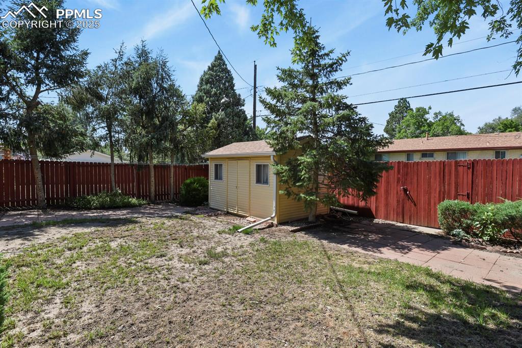 Image 25 of 26: Fenced backyard with an outbuilding