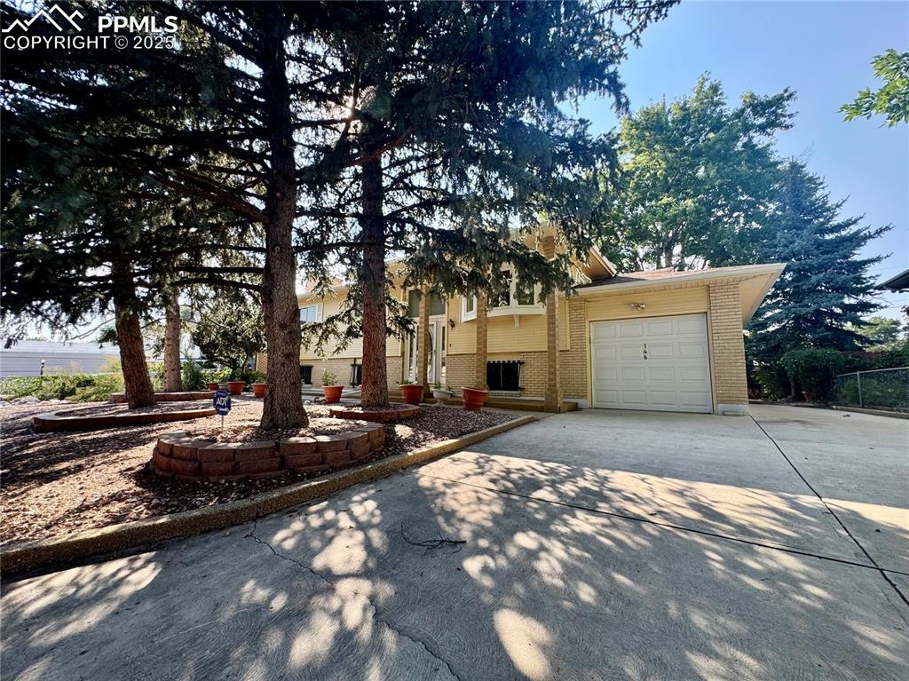 Image 4 of 26: Bi-level home with brick siding, concrete driveway, and an attached garage