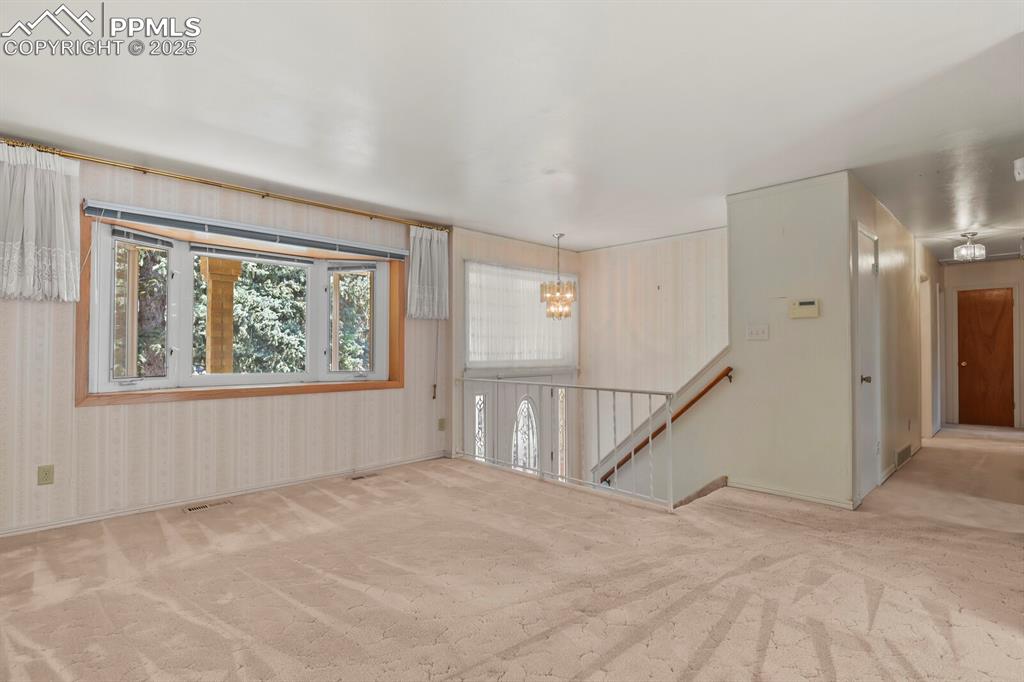 Image 7 of 26: Carpeted empty room with a chandelier and baseboards