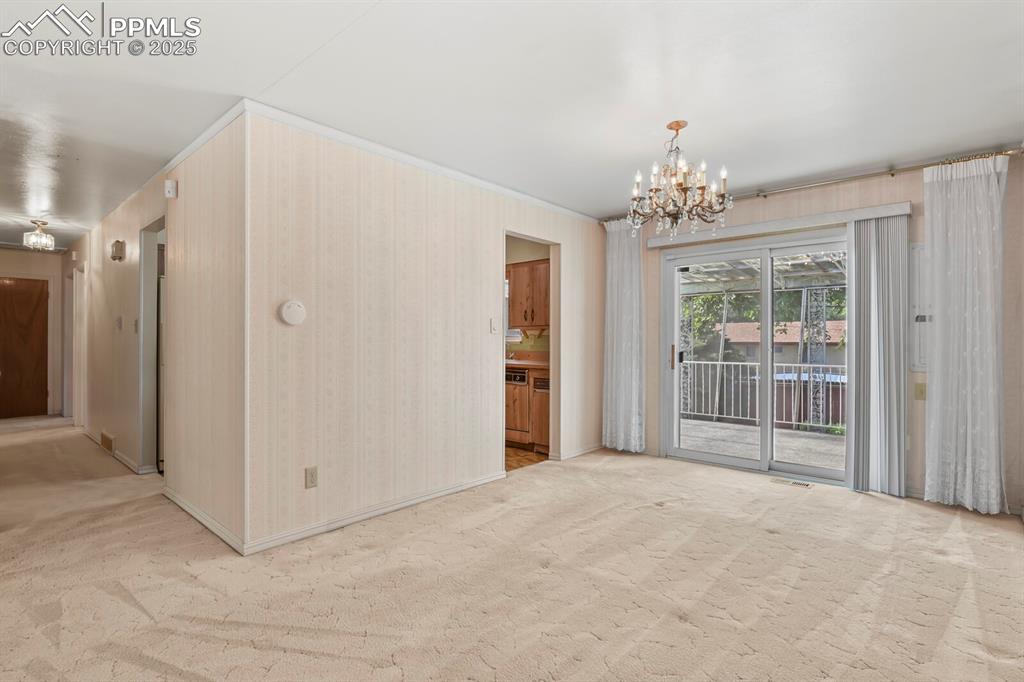 Image 8 of 26: Carpeted empty room featuring wallpapered walls and a chandelier