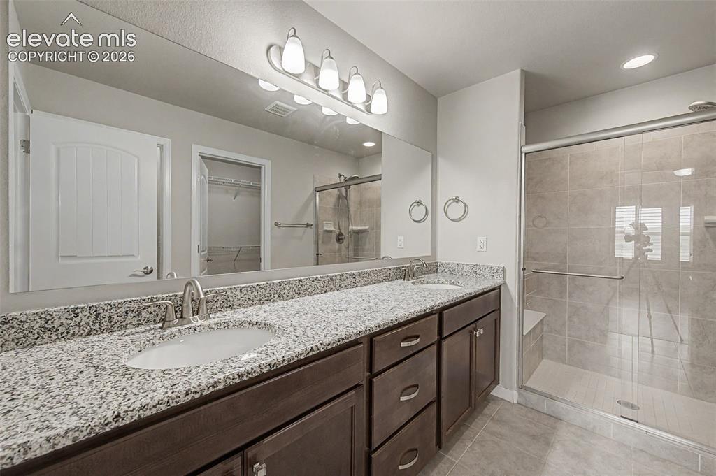 Image 16 of 28: Primary bathroom features a double vanity with granite counters, free-stand