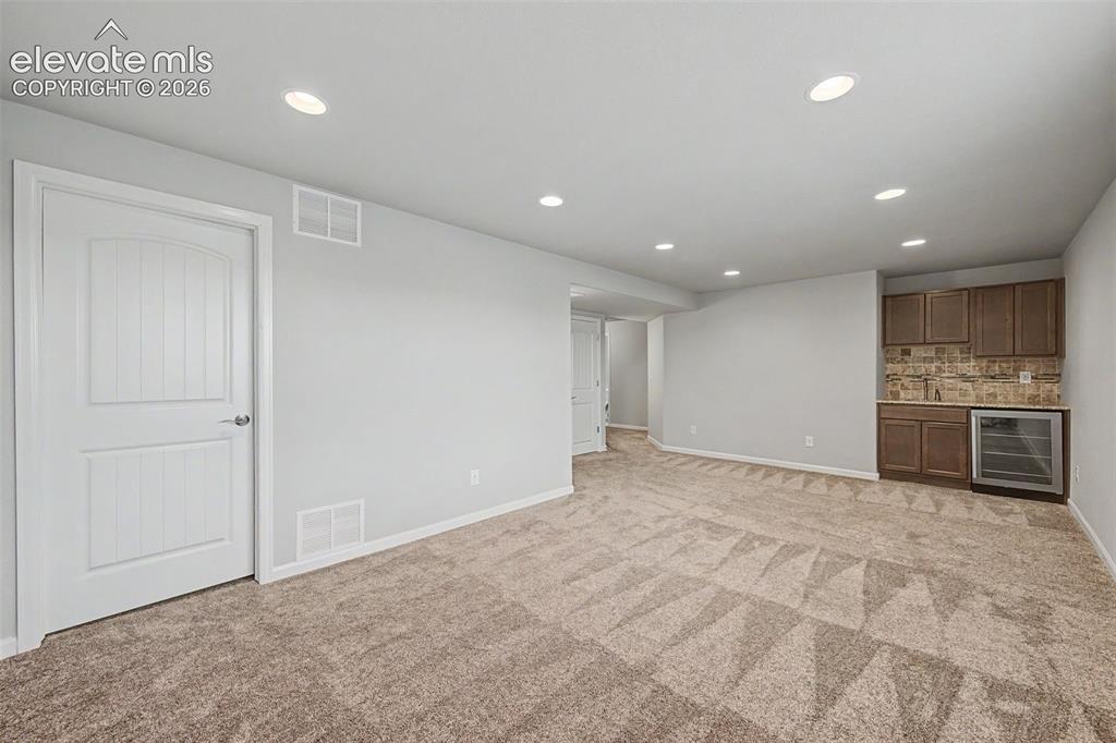 Image 19 of 28: Spacious family room, featuring a wet bar and beverage fridge