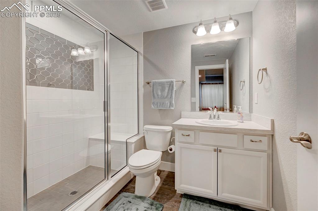 Image 36 of 50: Full bath featuring visible vents, a shower stall, toilet, vanity, and a te