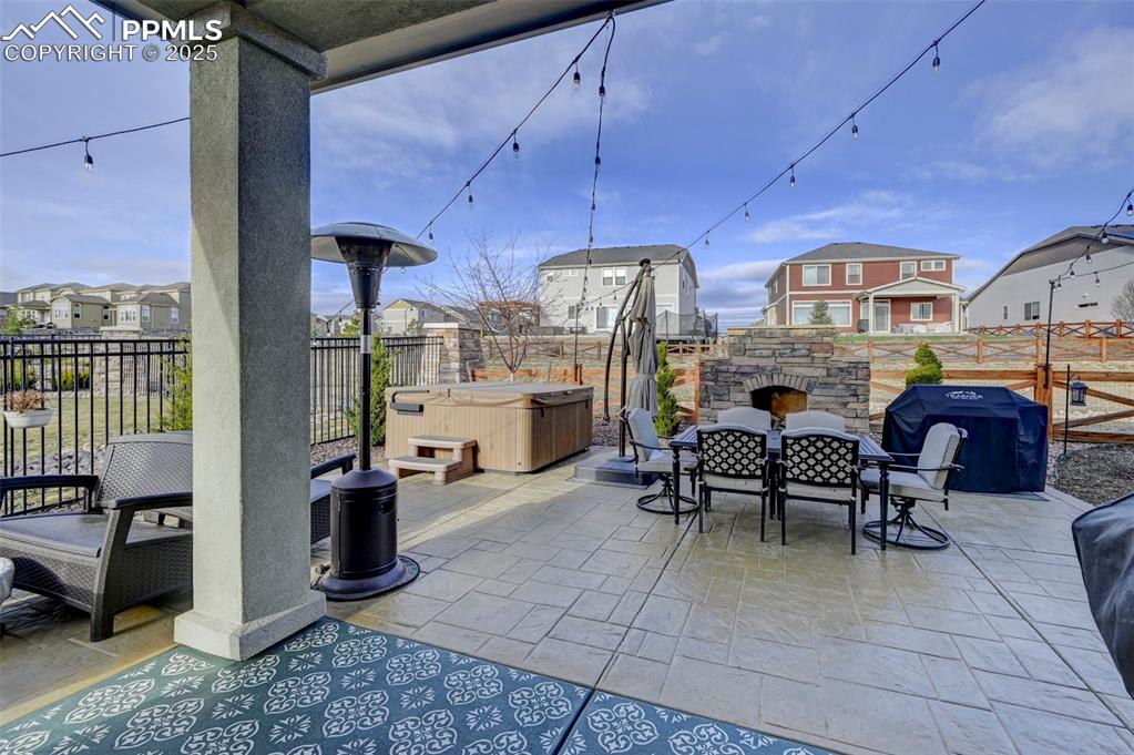 Image 43 of 50: View of patio / terrace featuring an outdoor stone fireplace, fence, and a