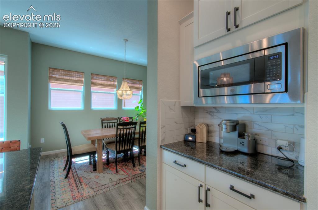 Image 12 of 35: Kitchen counter with dark speckled countertop, white cabinetry, a built-in 