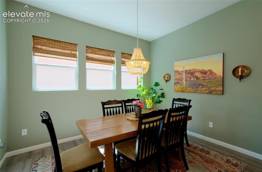 Image 13 of 35: Dining area with a vaulted ceiling, wood-finish flooring, three windows wit