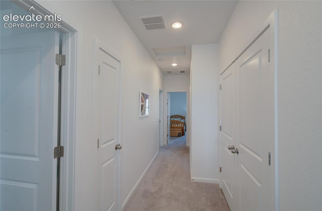 Image 17 of 35: Carpeted hallway featuring white paneled doors, recessed lighting, and a ce