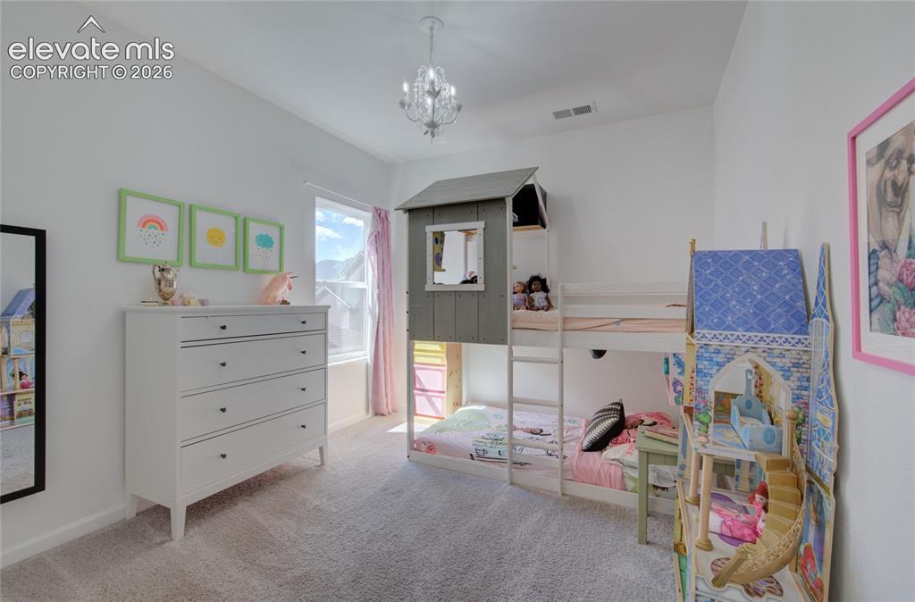 Image 20 of 35: Carpeted room featuring a double-pane window with natural light, a chandeli