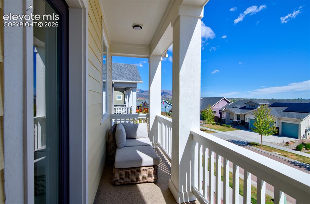 Image 25 of 35: Covered balcony with white railing and columns, yellow siding, and a visibl