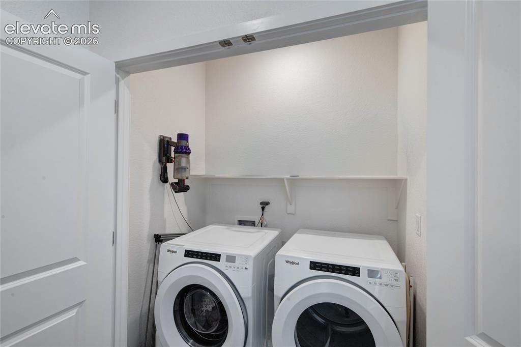 Image 27 of 35: Dedicated laundry closet featuring a built-in shelf and modern appliances
