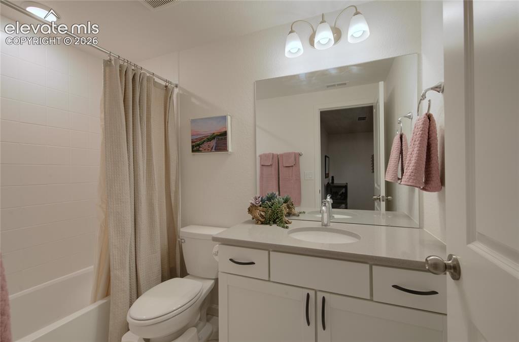 Image 32 of 35: Bright bathroom featuring a white vanity with a gray countertop, an integra