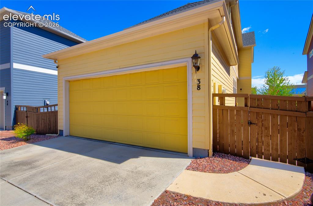 Image 35 of 35: Attached two-car garage with a bright yellow door, complemented by light ye