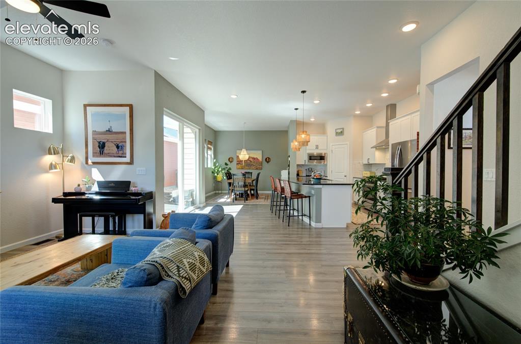 Image 5 of 35: Open-concept living area with wood-finish flooring, recessed lighting, and 
