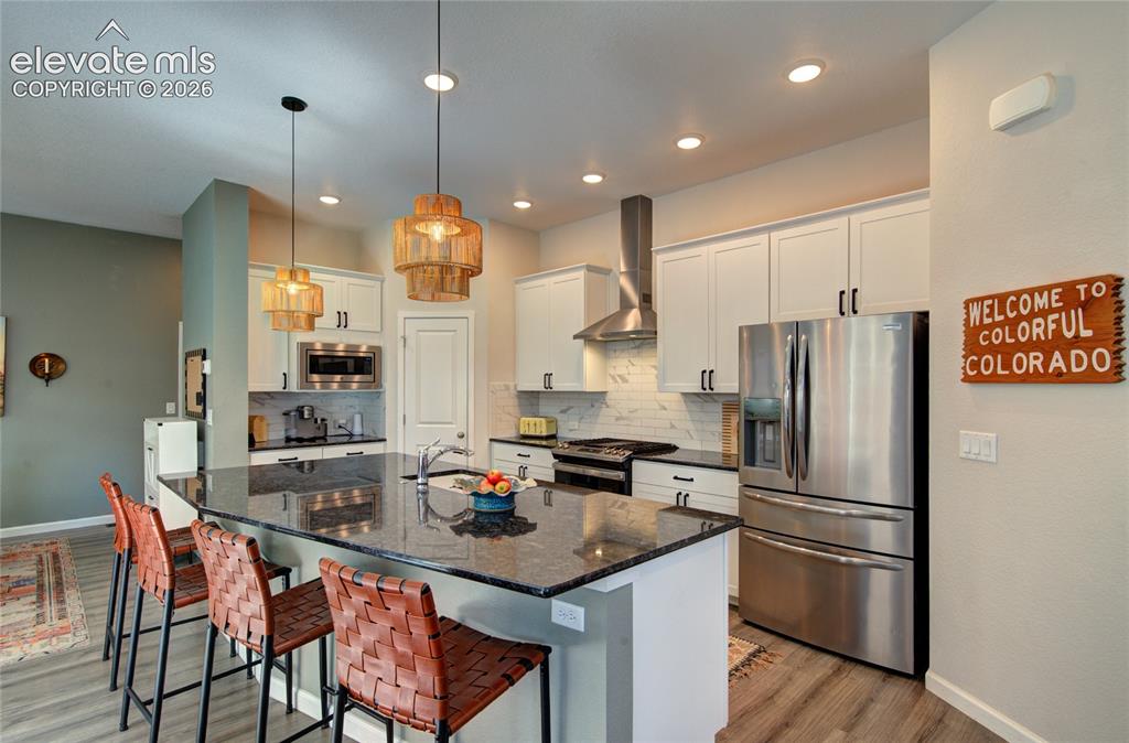 Image 9 of 35: Kitchen featuring a large central island with a dark countertop, white shak