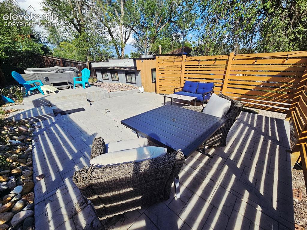 Image 23 of 37: Multi-level stamped concrete patio with privacy fencing, and spa