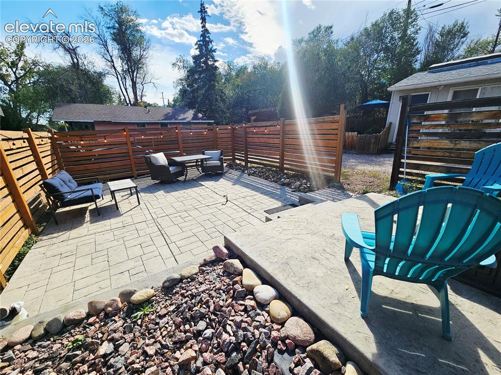 Image 24 of 37: Stenciled concrete patio with a tiered rock garden and wood privacy fencing